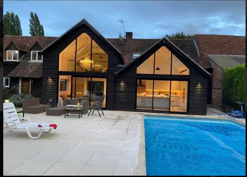 Timber-clad house with two tall glazed gables overlooking a pool